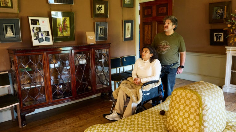 Two people, one of whom is in a wheelchair, are looking around the